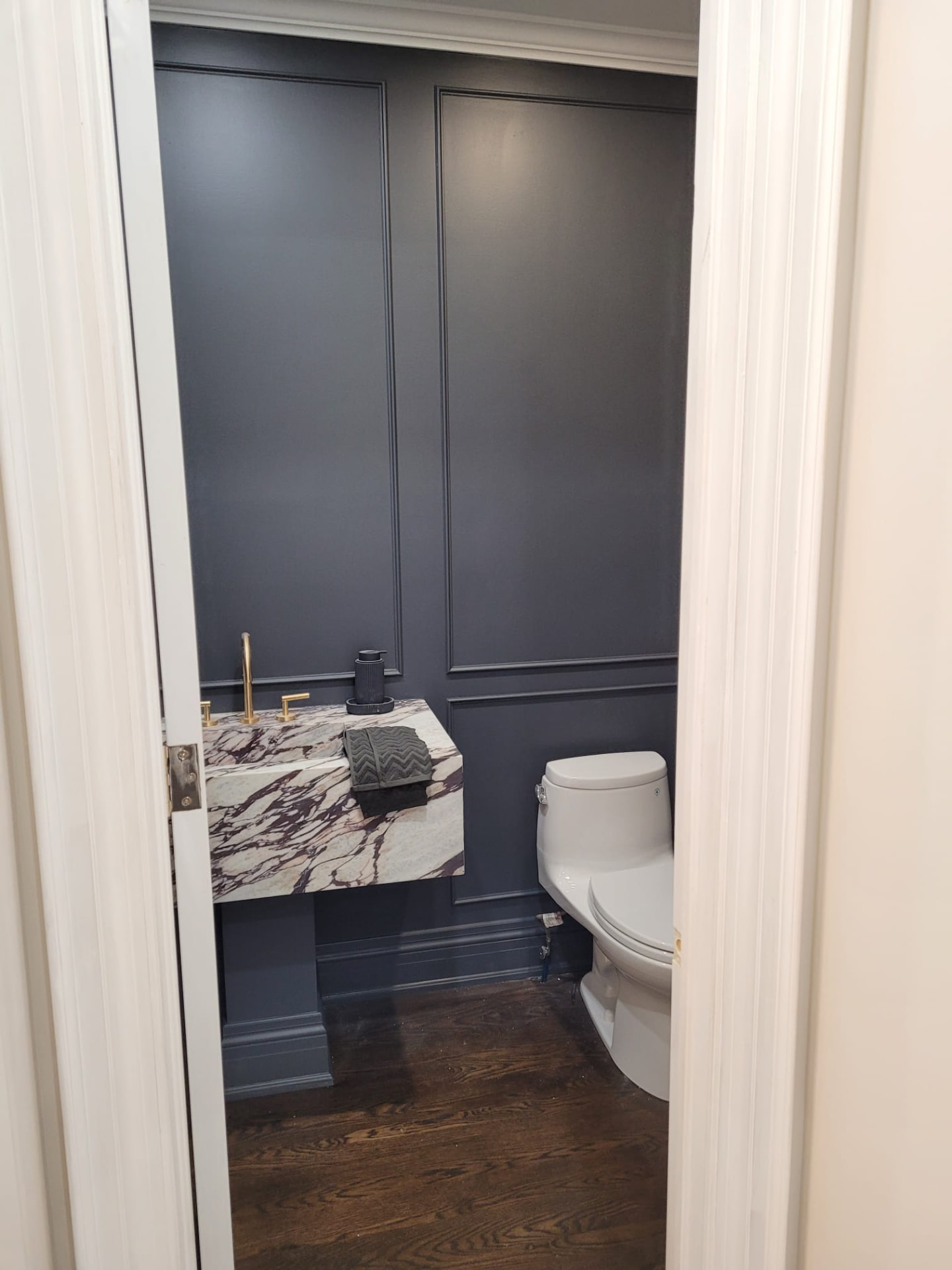 After photo of a Huntersville NC powder room with dark designer paint, custom wall moulding, and a floating stone vanity
