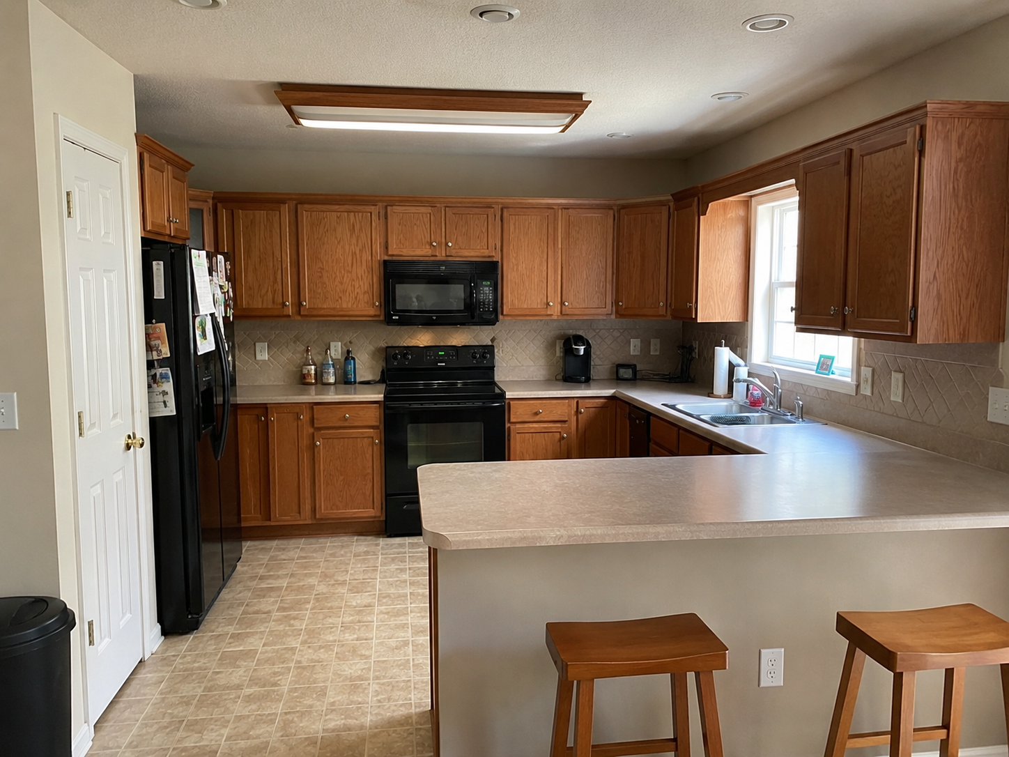 Before photo of dated Ballantyne kitchen with oak cabinets, laminate counters, and tile floor