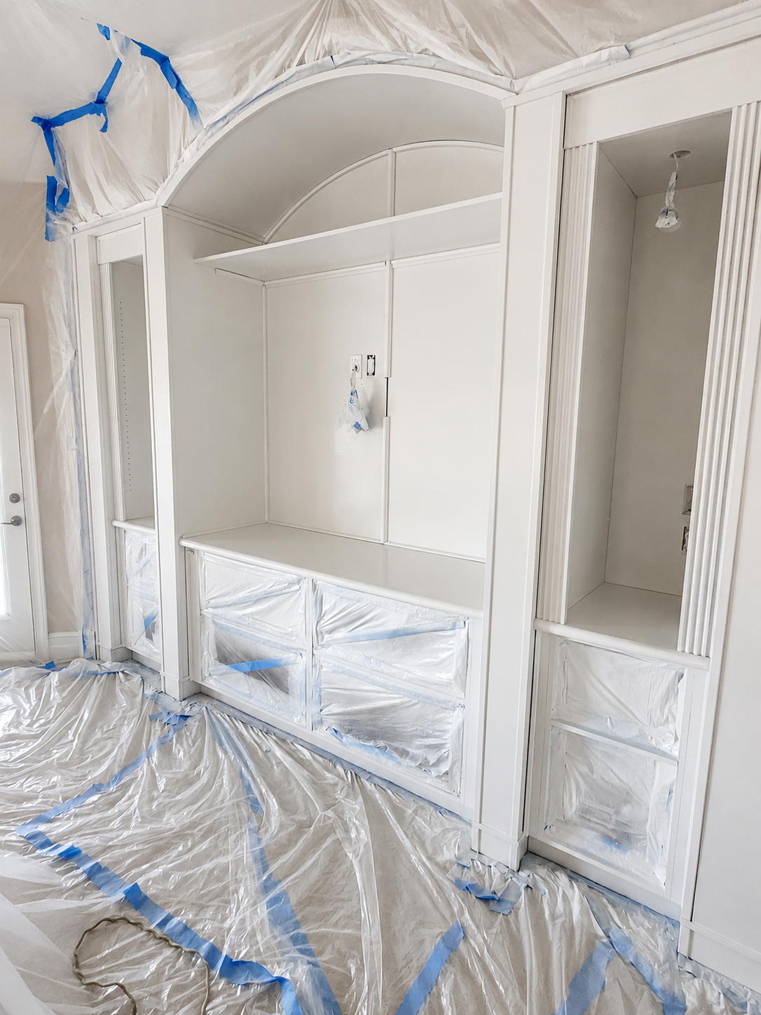 Before interior painting photo of a white built-in cabinet wall prepped with masking in Ballantyne NC