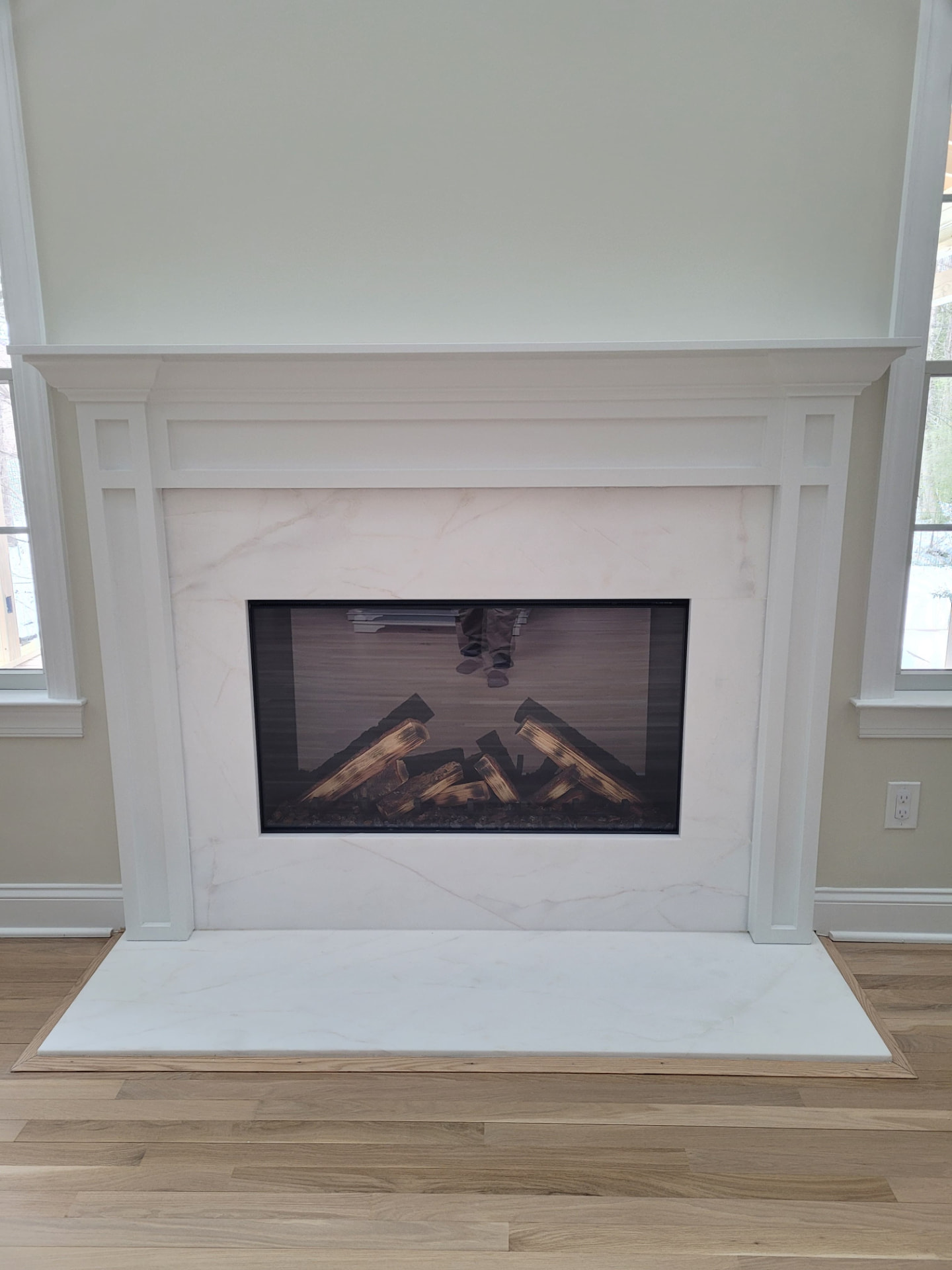 After photo of a finished white custom fireplace mantel and porcelain surround in Ballantyne