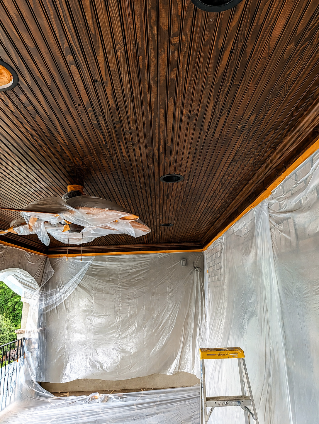 Before image of covered porch ceiling during renovation with unfinished ceiling boards and protective plastic in Charlotte NC