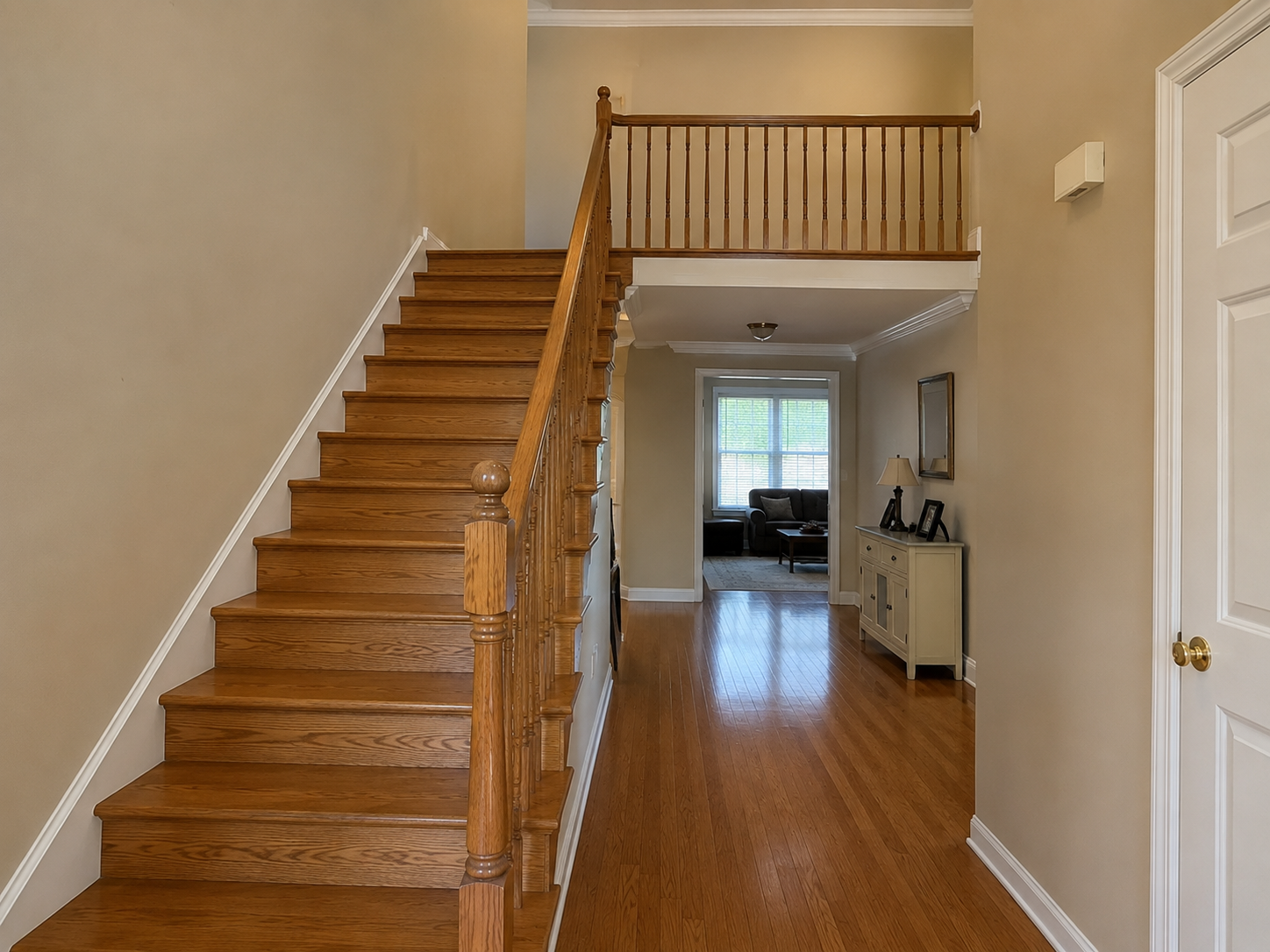 Before photo of Ballantyne staircase and foyer with honey oak treads, balusters, and railing